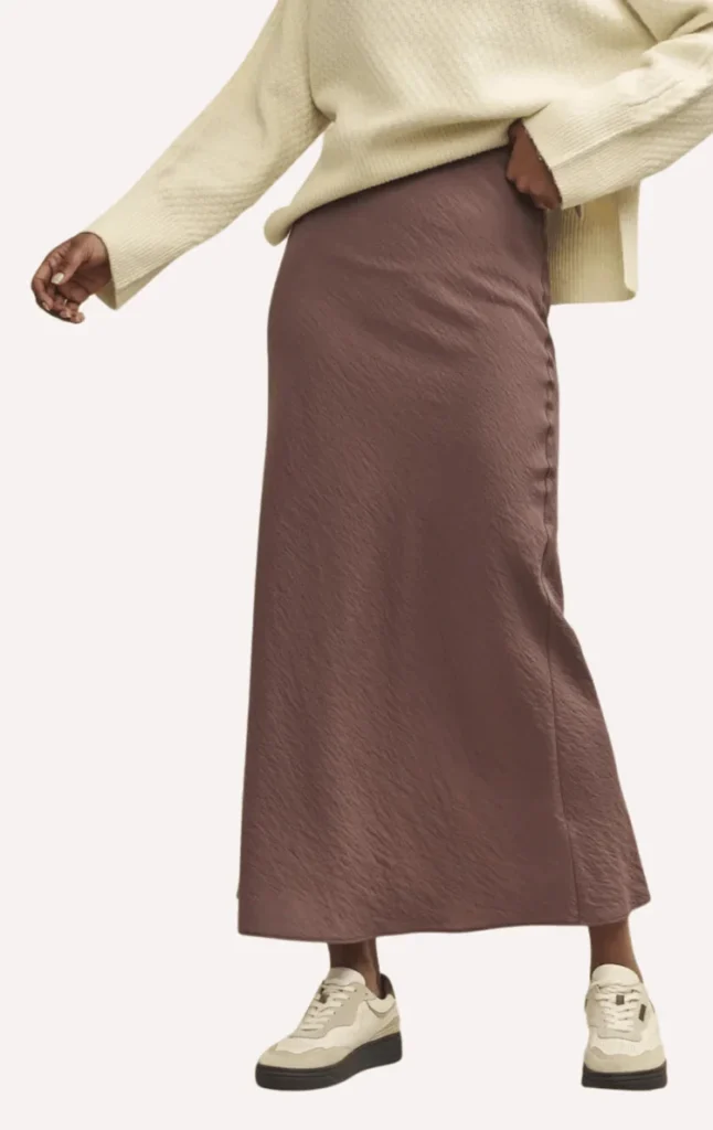 model wears brown midi skirt with an oversized cream jumper