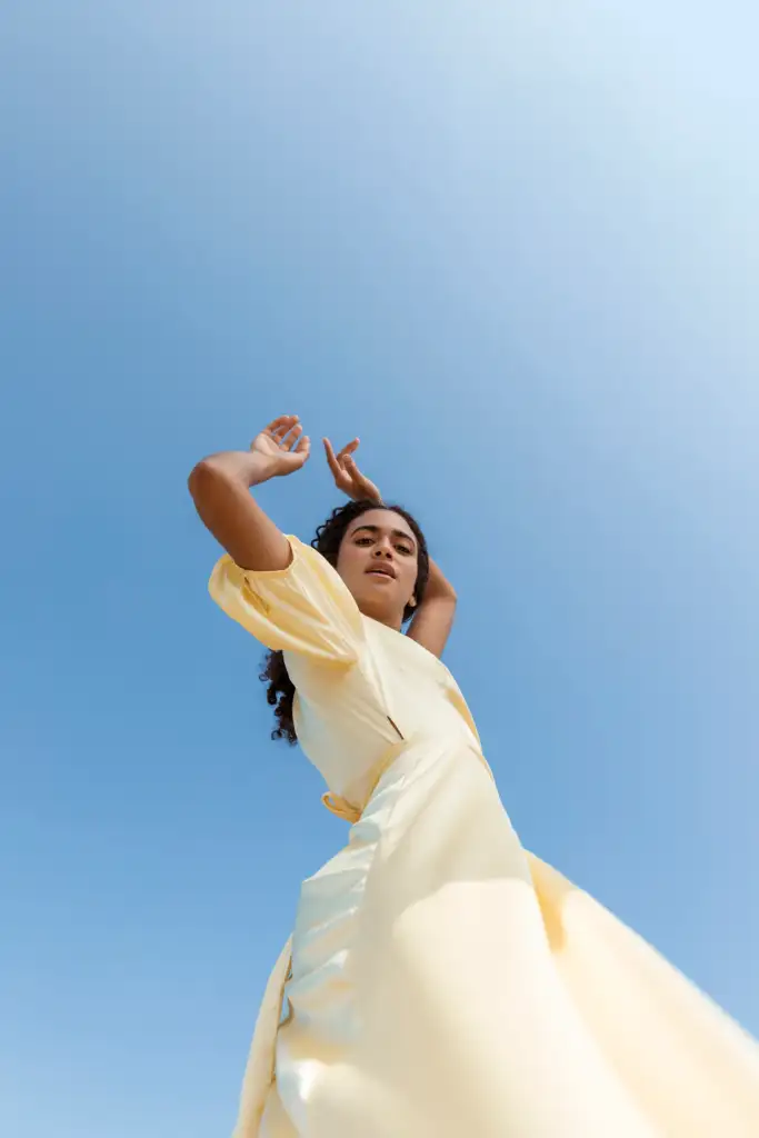 young woman dancing sky background. how to radiate feminine energy