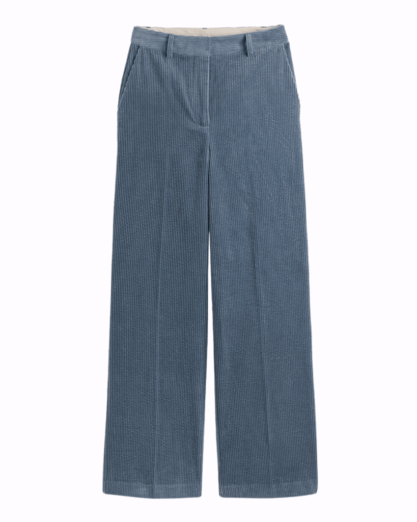 Blue corduroy trousers on a plain pastel pink background