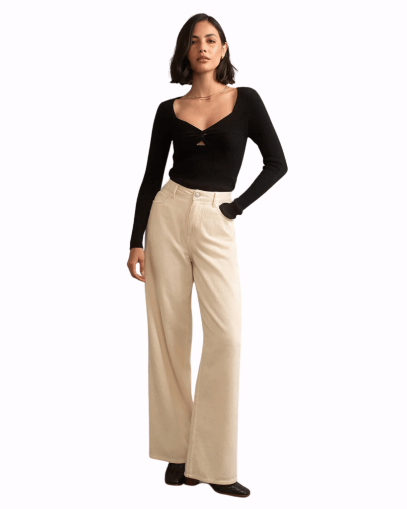 Model poses wearing cream corduroy trousers