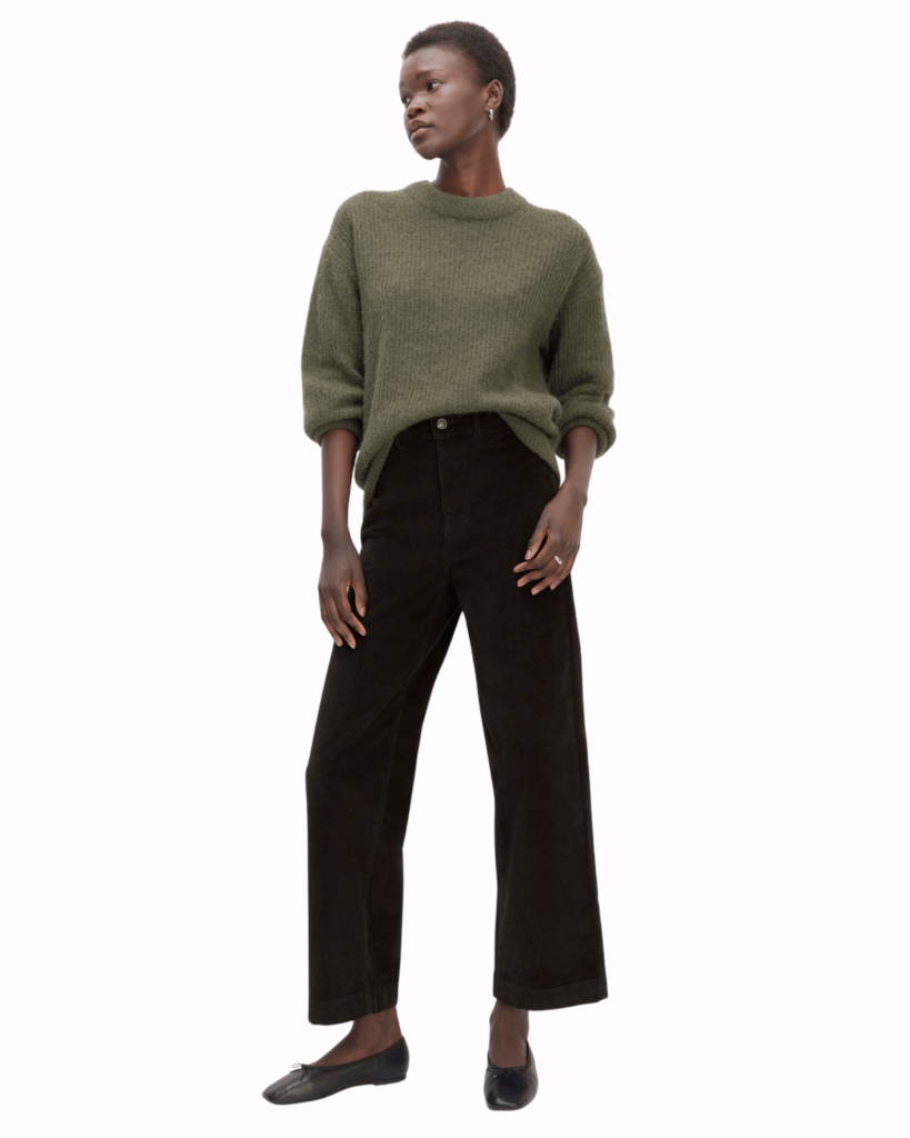 model poses wearing black corduroy trousers with khaki jumper