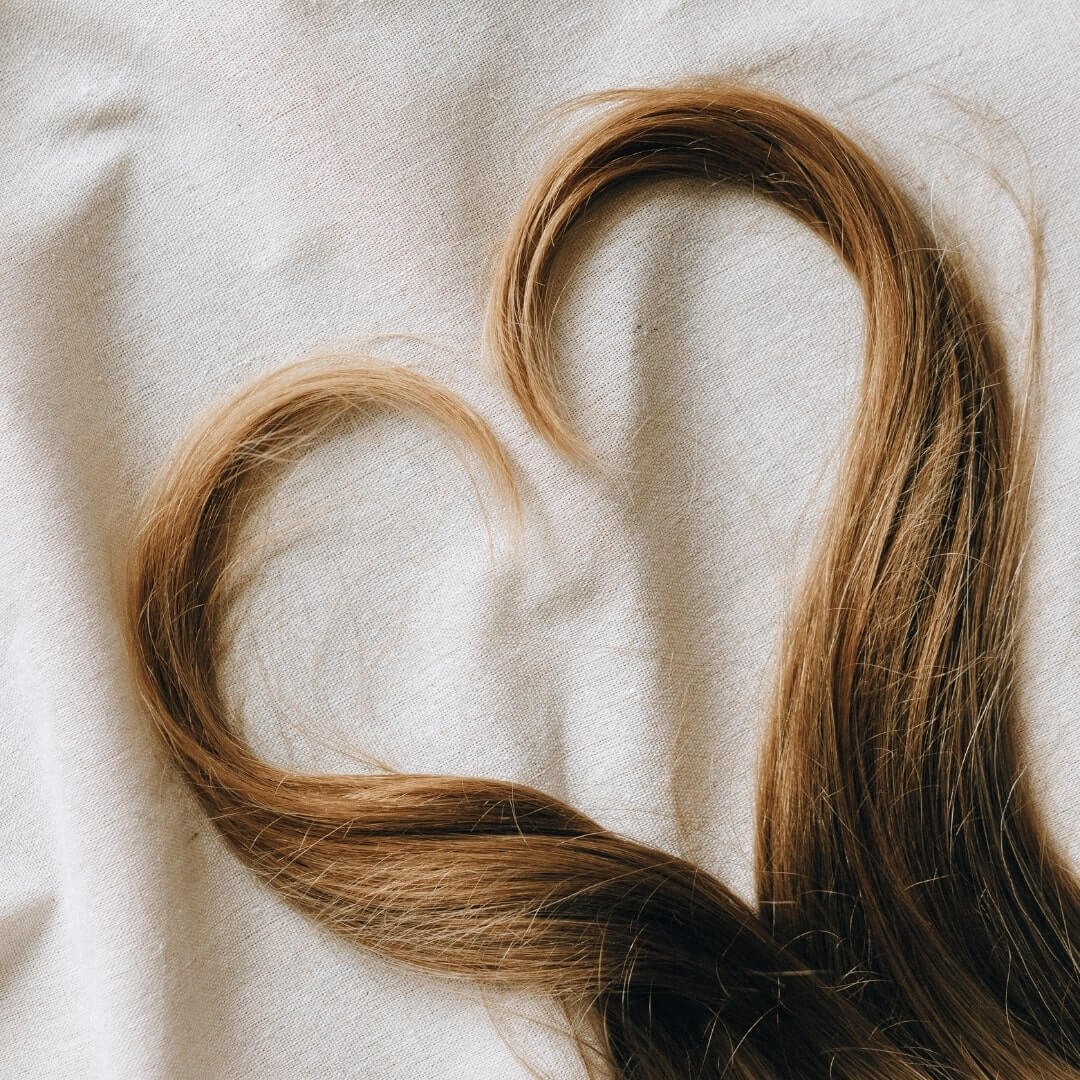 brown hair on white textile in a heart shape