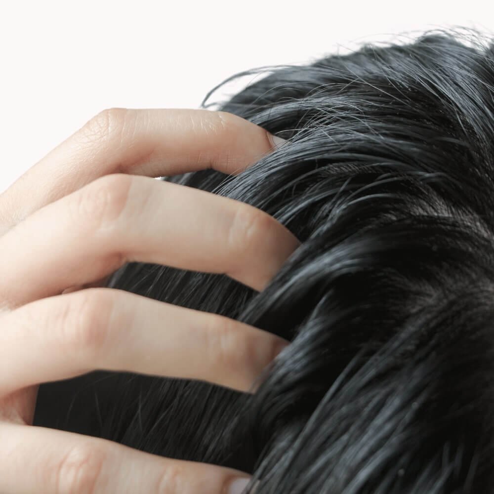 close up of a hand touching a scalp