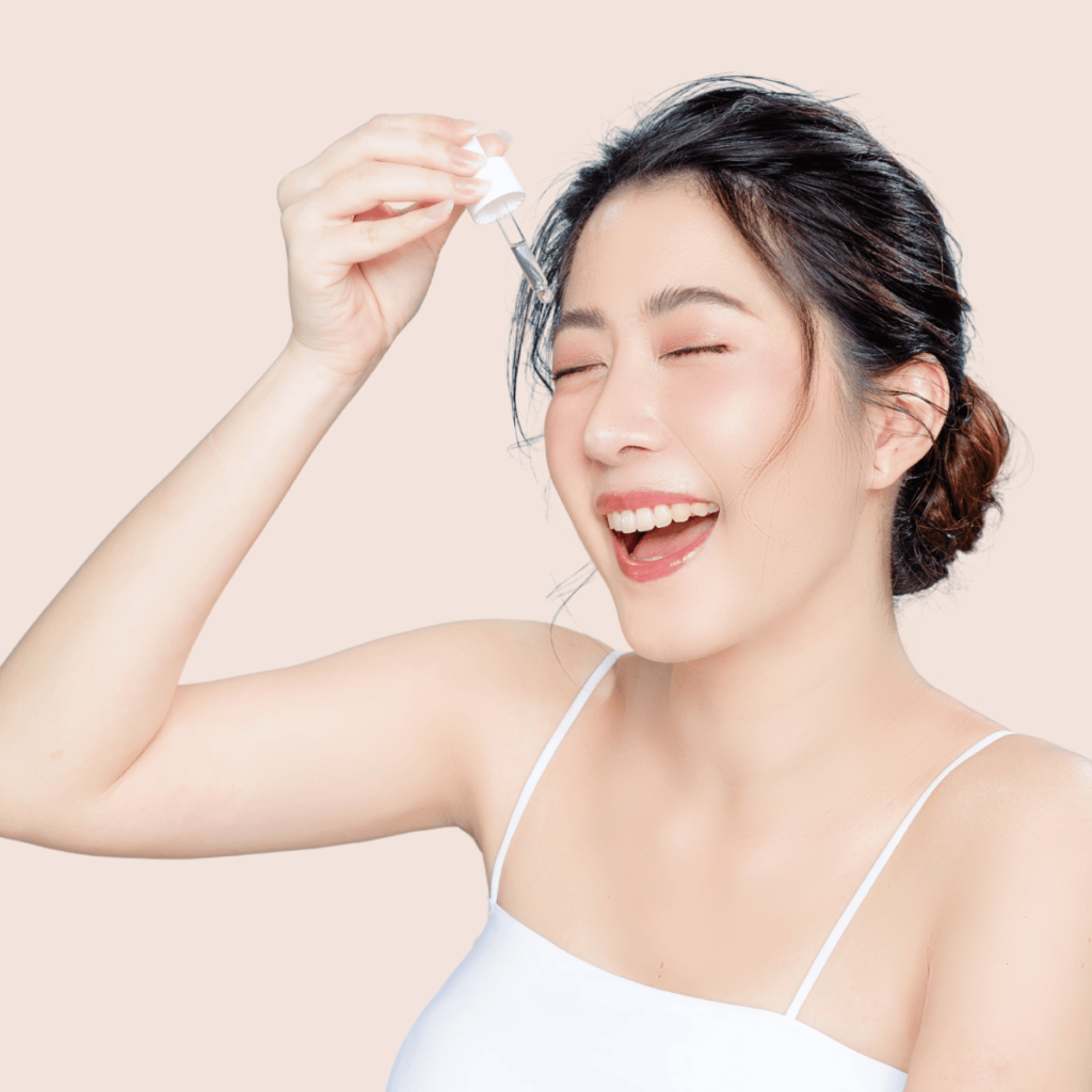 Asian woman applying oil to her face through cosmetic pipette. The 10-Step Korean Skincare Routine