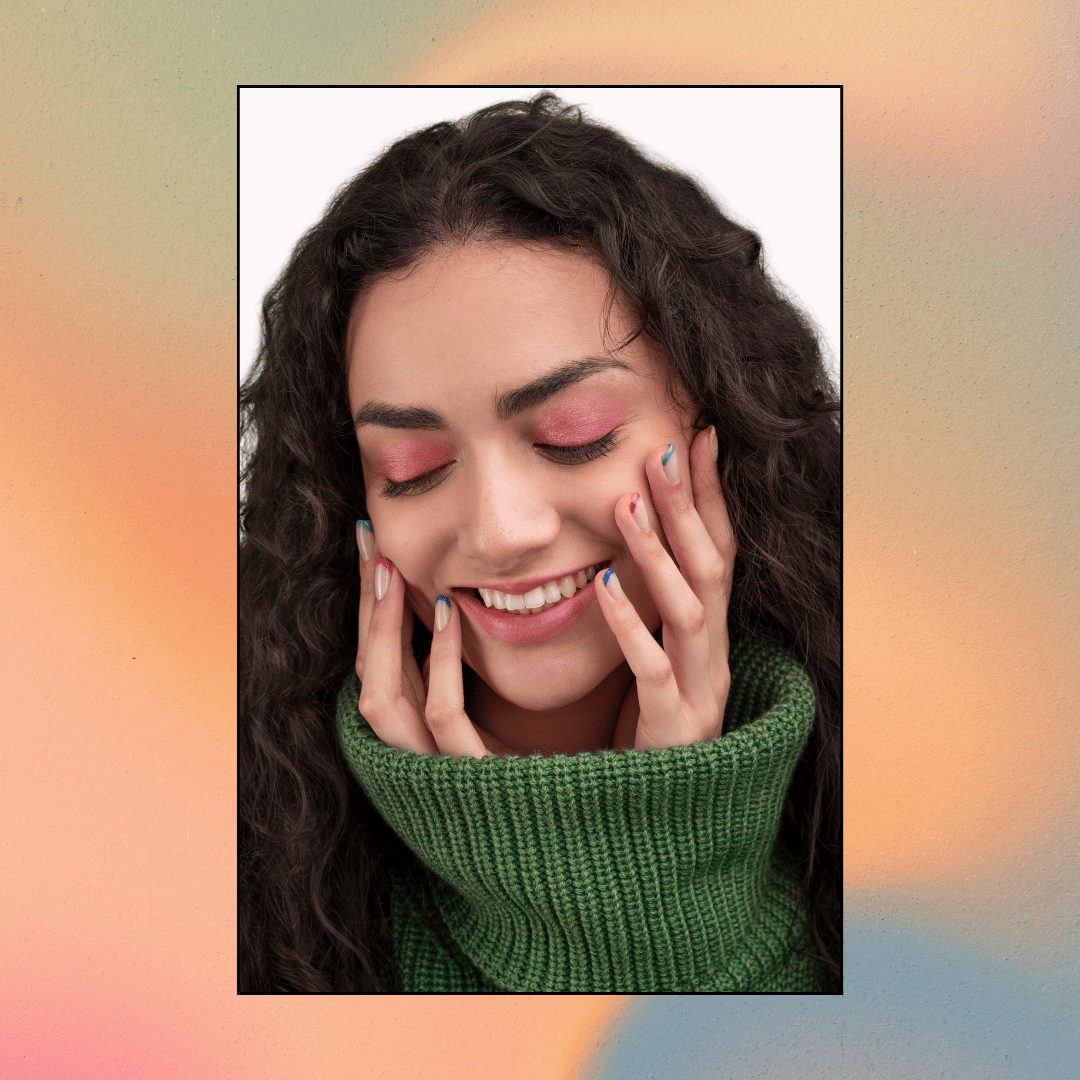 Woman with manicured nails touching her face.