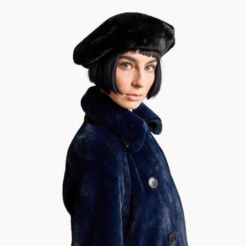 model weaing a vegan fur beret hat and matching navy blue jacket