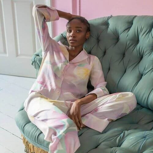 Model wearing satin nightwear on a sofa. Vegan Luxury Brands