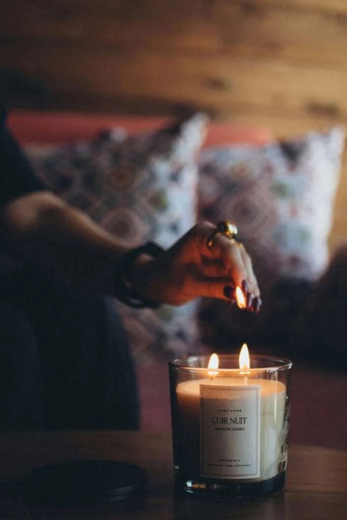 Person lighitng a candle in a dimly lit room. Saturday self-care routine