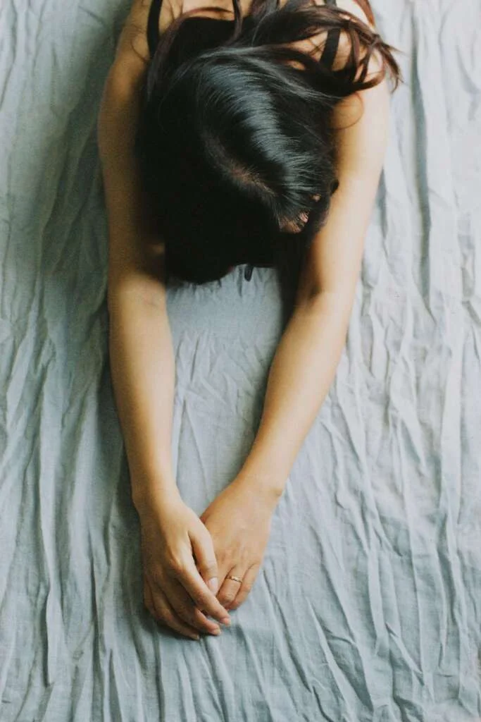 Woman stretching her arms out on her bed. 