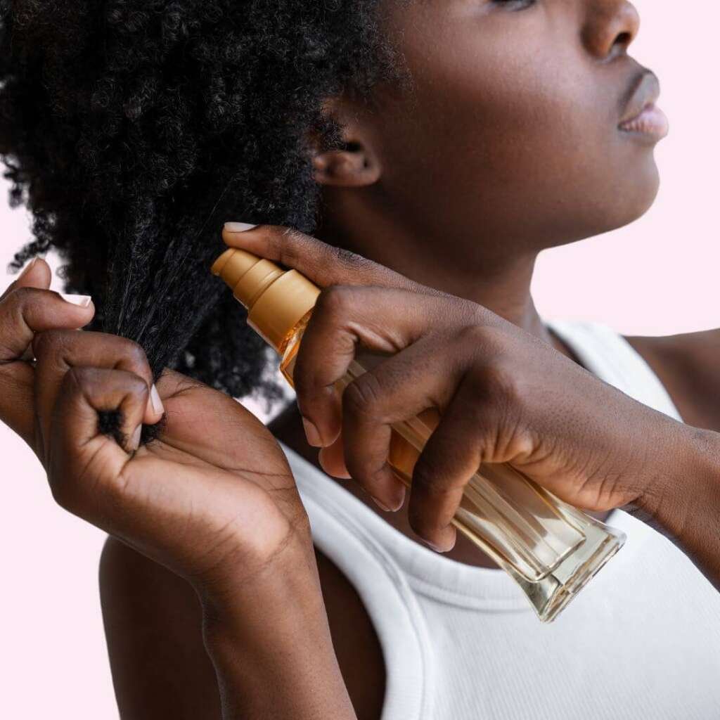 Woman spraying oil into her afro hair. Best oils for high porosity hair