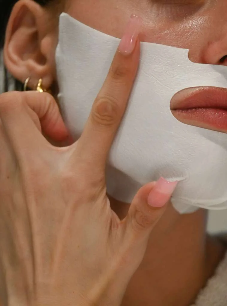 woman applying a sheet mask to her face. Saturday self-care routine