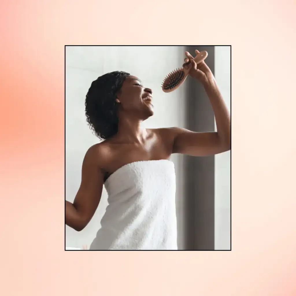 Black Young Woman wrapped in a towel Enjoying Haircare Singing with Hairbrush