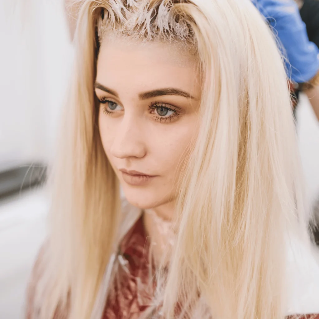 young blonde woman having her hair down at the hairdresser. Keratin Treatment on Bleached Hair