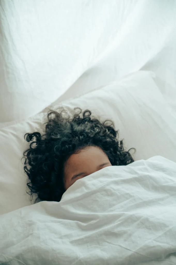 woman with wavy hair in bed with half her head showing