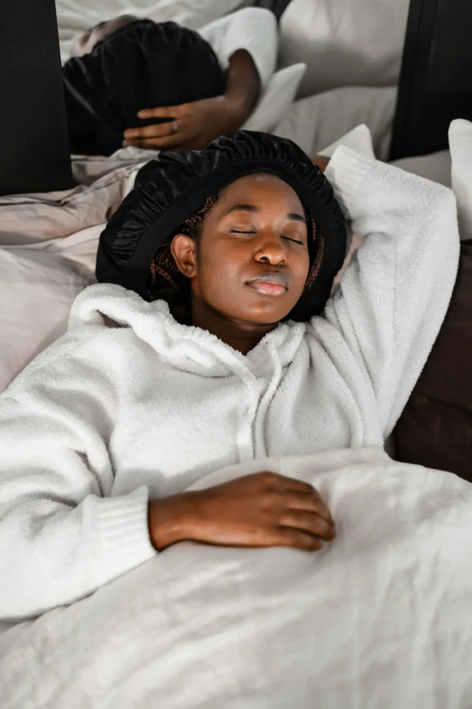 Black woman wearing a bonnet in bed