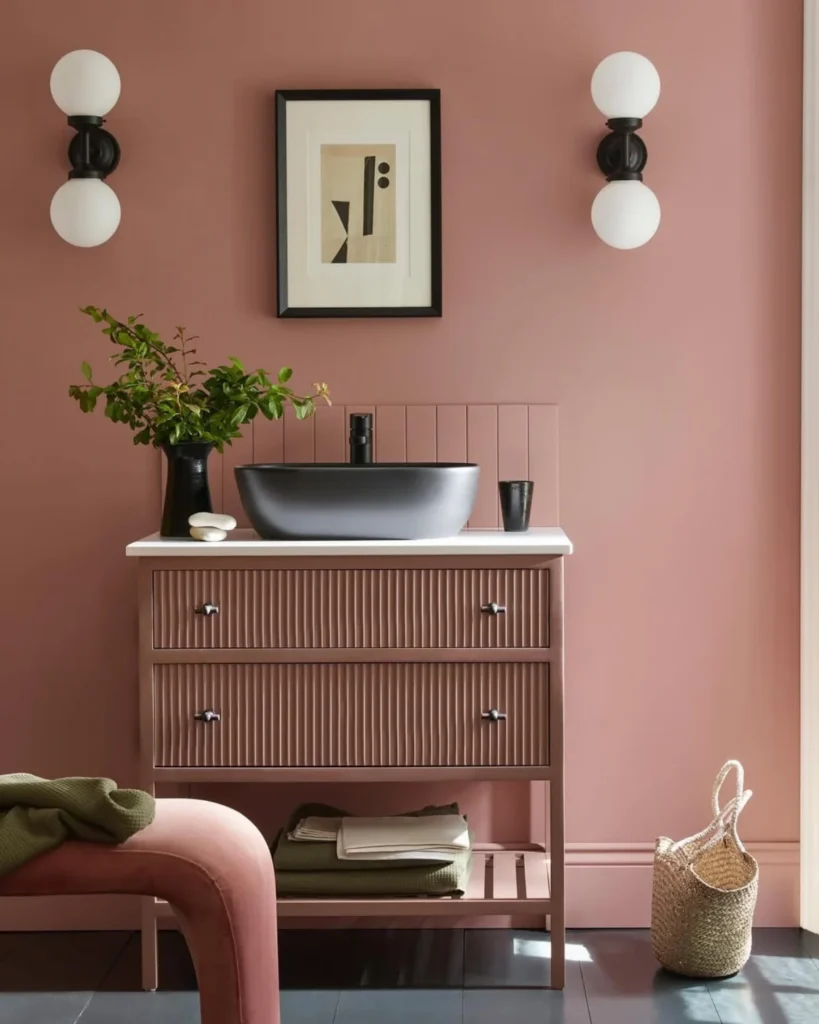 Pink bathroom with a black basin and wall lights