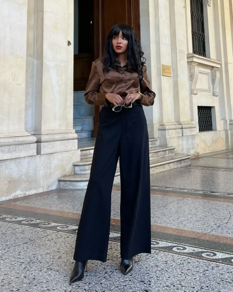 Tall black woman wearing a brown sating blouse and black trousers