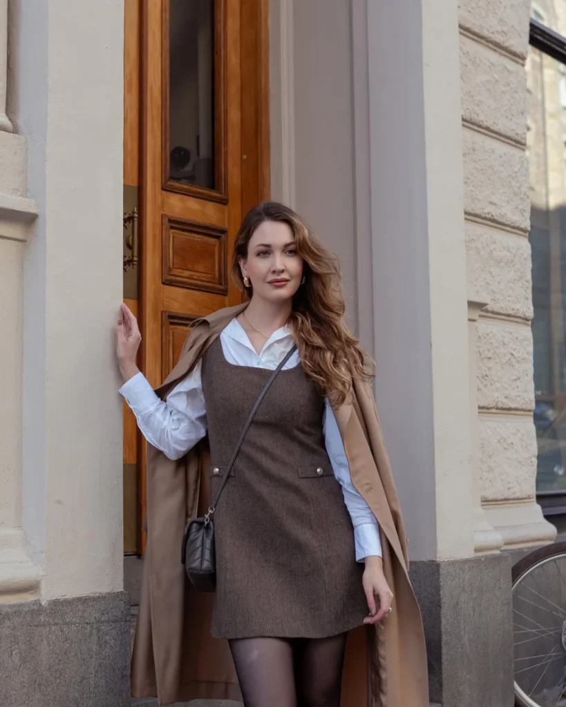 Woman wearing a brown dress with a white blouse and brown parka coat